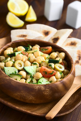 Salat aus Kichererbsen, grünen Oliven, Gurken, Kirschtomaten und Petersilie in Holzschüssel serviert, fotografiert mit natürlichem Licht (Selektiver Fokus, Fokus ein Drittel in den Salat)
