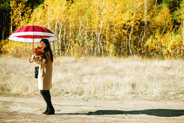 woman walk in autumn forest with umbrella