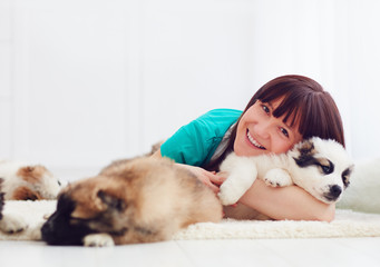 happy girl lies on carpet with caucasian shepherd puppies