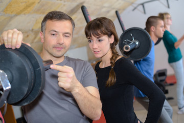 Fototapeta na wymiar trainer explaining how to use training machine in a gym