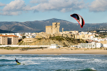 Man practicing kitesurfing on the beach of Tarifa, Spain. Tarifa is considered the capital of the wind, and favorite place for lovers of this sport. - obrazy, fototapety, plakaty