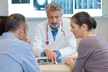 Doctor looking at xrays with couple