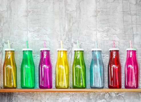 Colorful bottles on the wooden shelf with grey concrete wall background