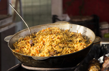 Cooking pilaf dish in outdoor.  in a cauldron, street food