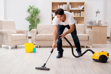 Fototapeta na wymiar Man cleaning home with vacuum cleaner