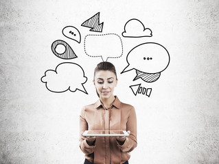 Woman with tablet and speech bubbles on concrete
