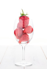 fresh strawberry in wine glass isolated on white wood