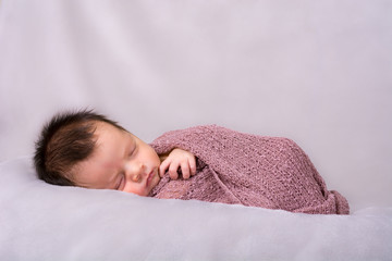 Beautiful newborn baby girl swaddled in a knit wrap