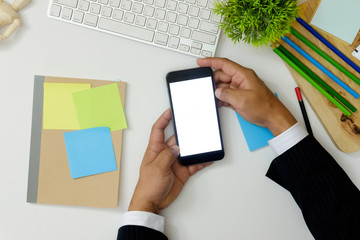 Start up Concept. Businessman looking Blank screen of smartphone in hands on white work table.