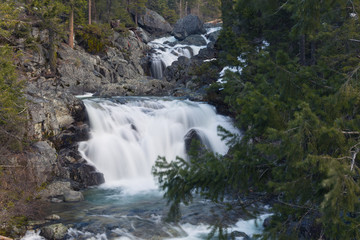 Fototapeta na wymiar Long exposure of a small waterfall full of spring snowmelt in a granite canyon in the Trinity Alps