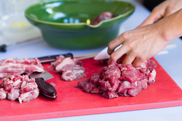 chopped meat food processing in the kitchen with knife with red chopping board