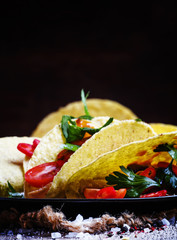 Mexican tacos stuffed with meat, beans, tomatoes and chili peppe