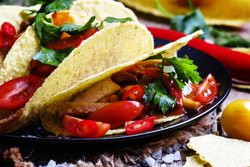 Mexican tacos stuffed with meat, beans, tomatoes and chili peppe