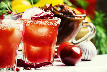 Tomato cocktail with pepper vodka, orange juice and ice, wooden