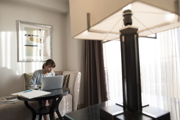 The lady is using a laptop computer in the hotel room