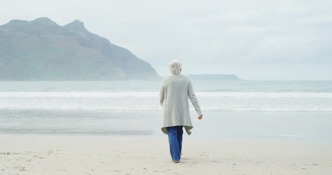 Rear view of senior woman walking on beach