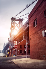 New York City street in Brooklyn with view to Williamsburg Bridge at sunset time. Old architecture buildings.