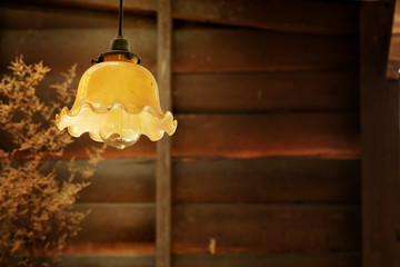 retro hanging lamp in vintage style with rough wooden wall decorate by Dry grass   background 