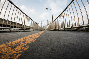 Obraz premium Wide angle view of straight yellow line on bitume floor, footbridge, walkway and stairs, perspective with vanishing point, city urban background 