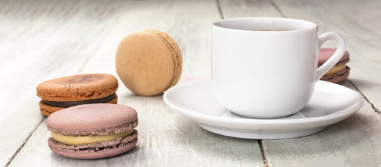 Cup of coffee with pastel colored macarons and copyspace
