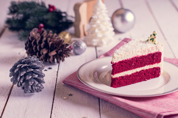 Christmas cake on plate on red fabric on wood background and dec