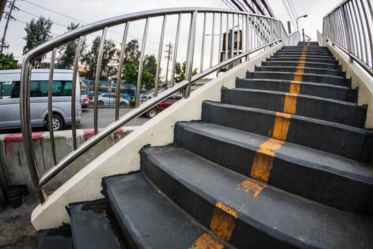 Wide angle view of straight yellow line on bitume floor, footbridge, walkway and stairs, perspective with vanishing point, city urban background 