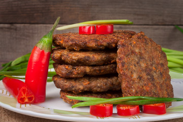 liver pancakes or cutlets with chili pepper and green onions on a wooden background