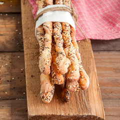 Fresh baked homemade grissini bread sticks on a wooden board