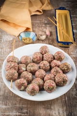 Raw meatballs on a white plate. Rustic weathered wood backgroudn