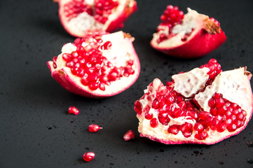 Whole and sliced pomegranate on a black background
