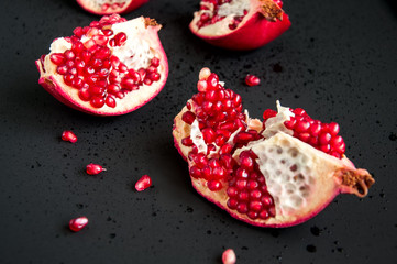 Whole and sliced pomegranate on a black background