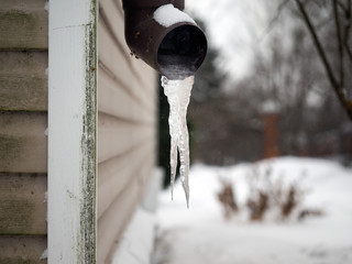 Frozen drain. Large icicles, snow, winter, house corner