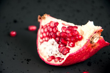 Whole and sliced pomegranate on a black background