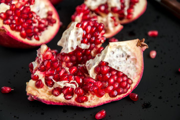 Whole and sliced pomegranate on a black background