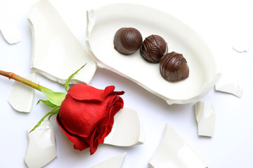 Red Rose and chocolates laying on a broken bowl