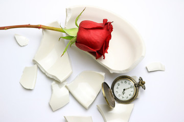 Red Rose and pocket watch laying on a broken bowl