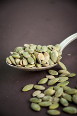 Pumpkin seeds in a spoon on a dark background