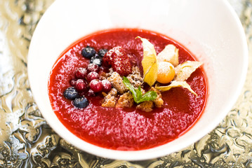 View on strawberry soup with fresh berry in white plate on table