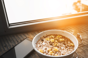 Breakfast, smartphone with white screen and headphones. Muesli