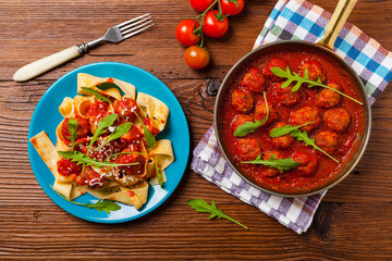 Italian pasta pappardelle with meatballs in tomato sauce.