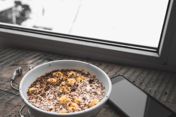 Breakfast, smartphone with white screen and headphones. Muesli
