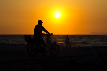 Fototapeta na wymiar Motorcyclist on the beach during the sunset, Greece