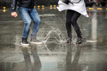 Wet shoes of couple, man and woman jumping in puddle
