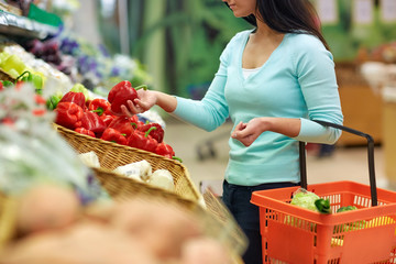 woman with basket buying peppers at grocery store