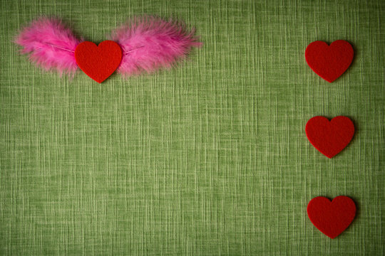 Felt heart and dyed bird feathers on fabric background, Valentine's card