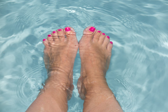 Pretty female feet in the pool on a summer holiday day