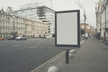 Vertical blank billboard on the city street. In background buildings and road with cars. Mock up....