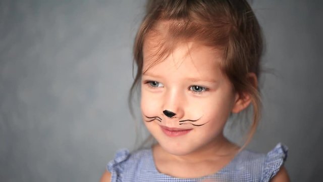 Baby 3 years with face painting of a cat, meowing and smiling