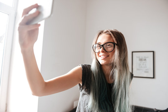 Happy yougn woman making selfie with cell phone at home