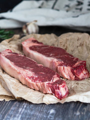 Two  fresh steak marbled beef on a paper substrate on a dark  wood background
